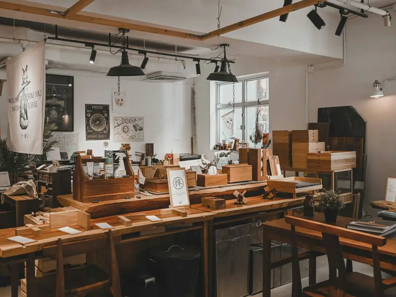 A furniture studio with finished pieces set out on long timber benches under track lights